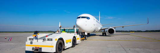 Aviation ground support equipment vehicle and airplane on a runway