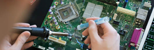 A person using a screwdriver and working on a computer board