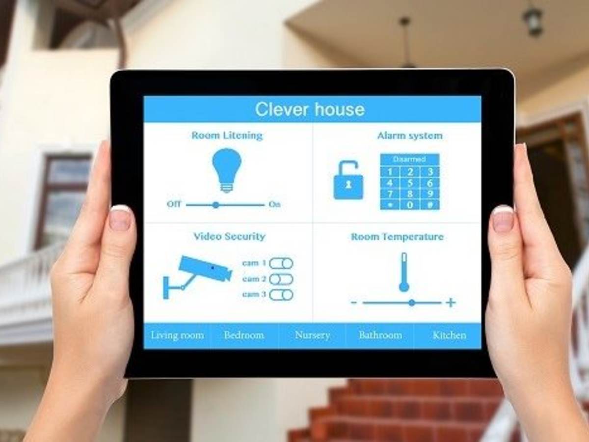 Female hands hold a tablet computer with system clever house on a screen on the background of the house