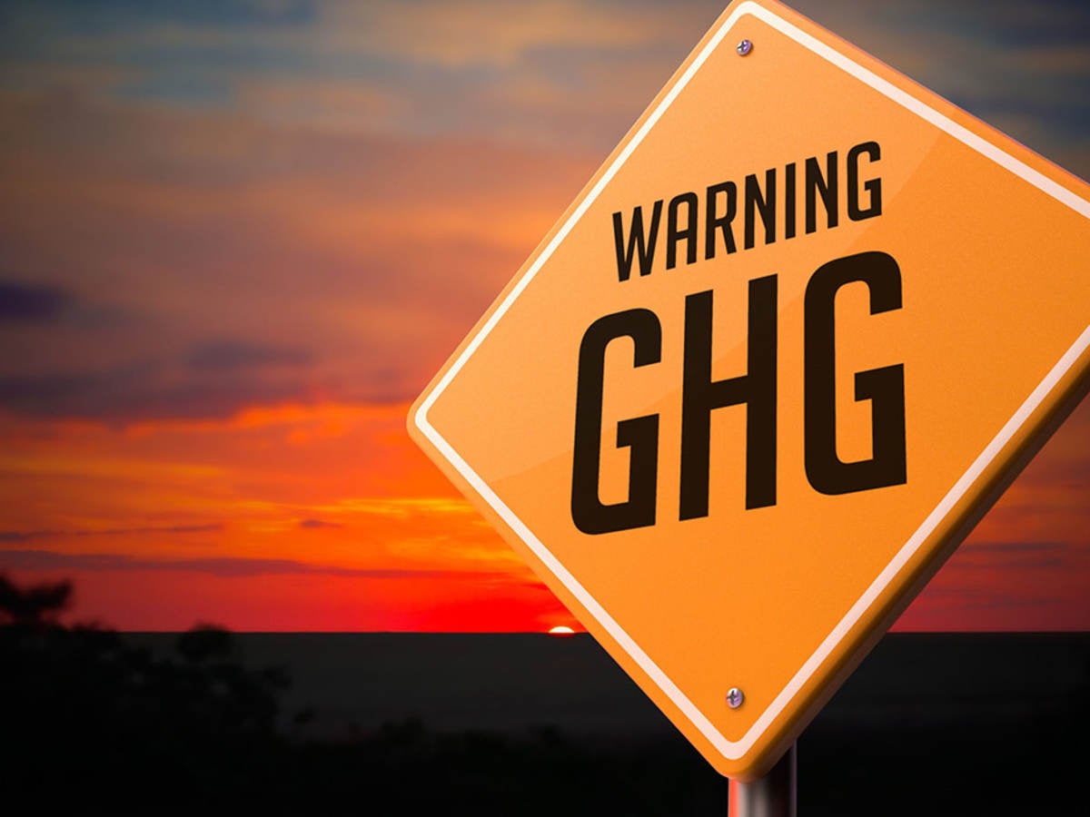 Greenhouse gas warning road sign on sunset sky background