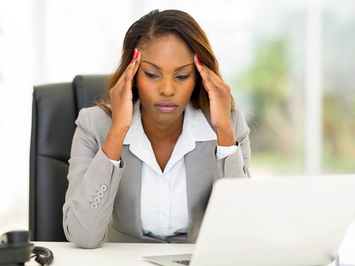 Stressed businesswoman sitting in office rubbing her head