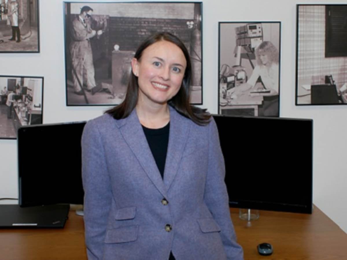 Justine Wagner relaxes in front of photo wall showing UL's history.