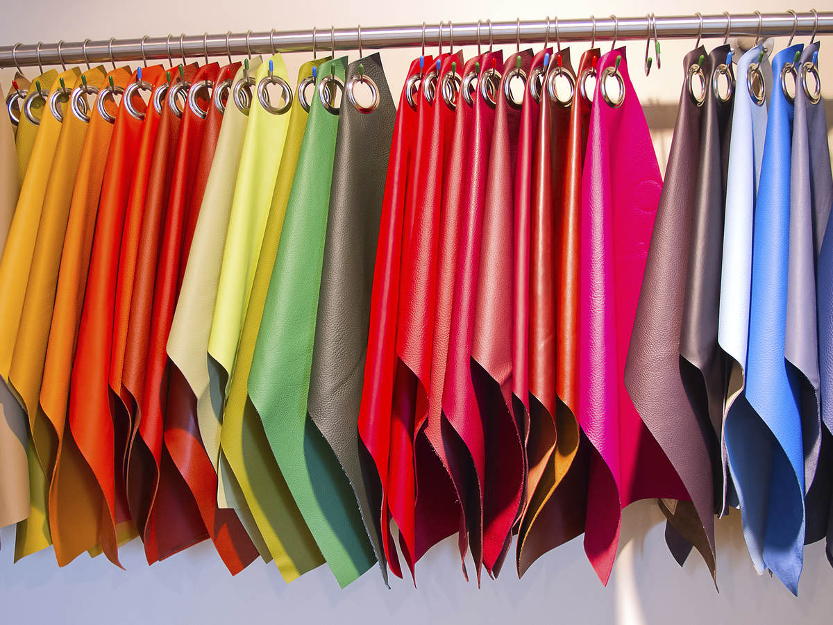A variety of different colored fabrics hang on a rack.