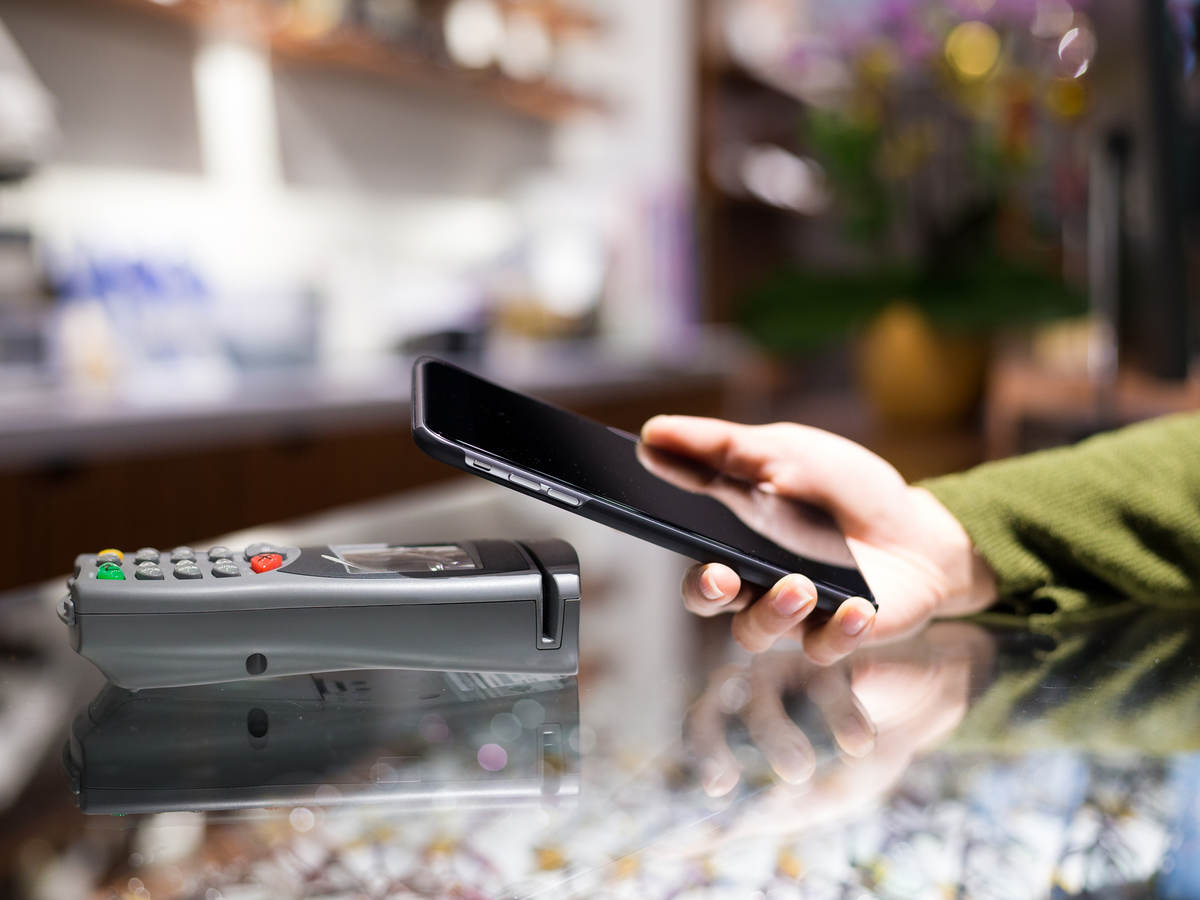 A person holding their smartphone up to a payment terminal.