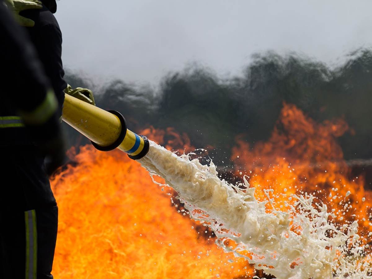 Firefighter spraying a fire with foam hose
