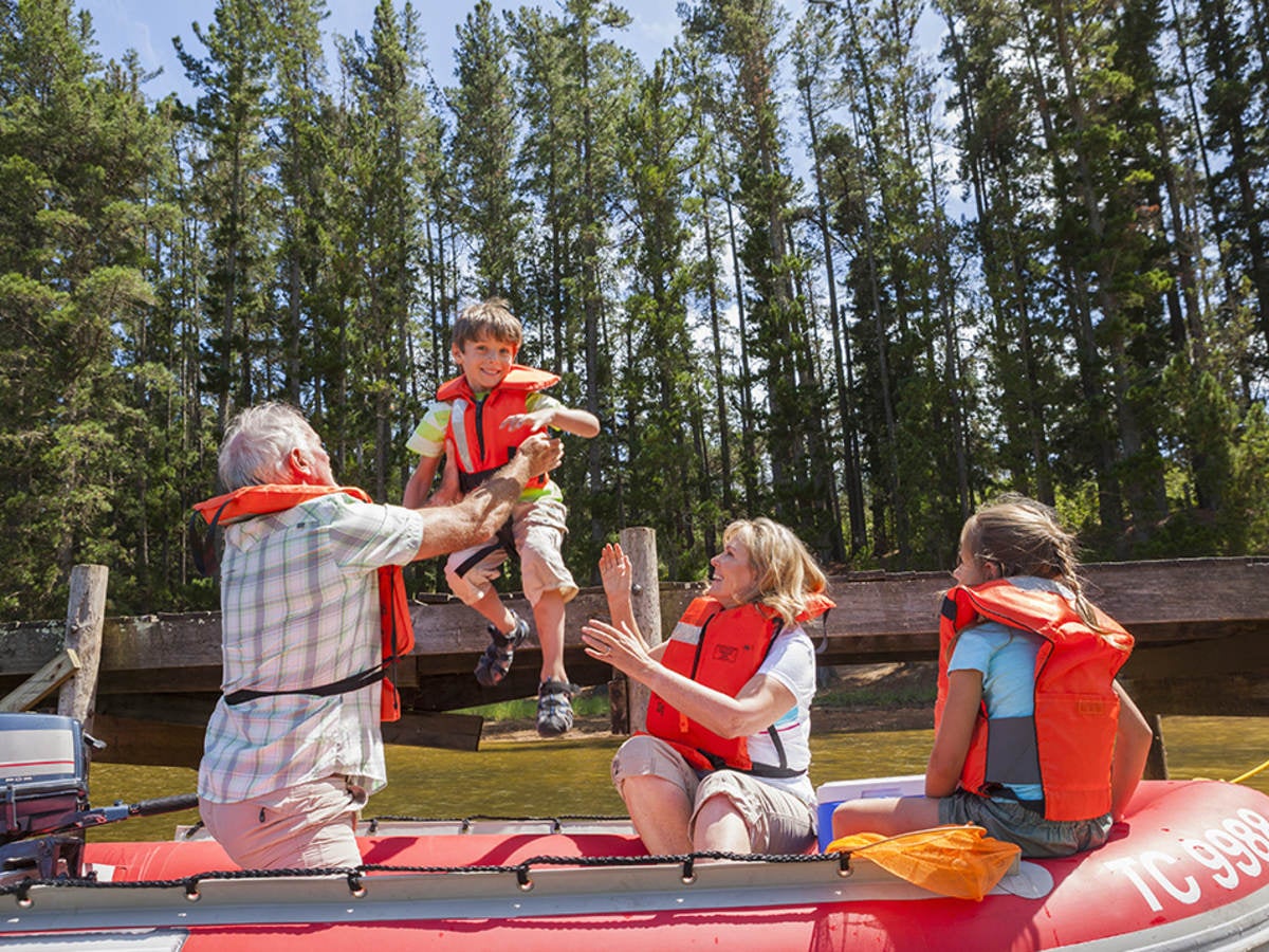 A family wearing orange life jackets boarding a boat. 