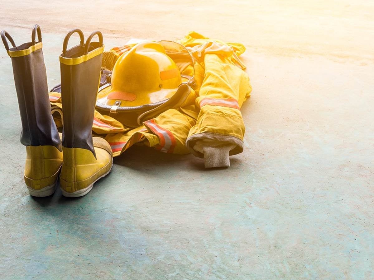 A yellow fireman’s uniform and boots laying on the ground. 