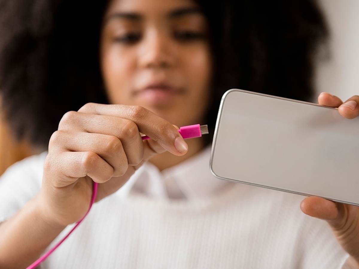 A person plugging a cord into a handheld device