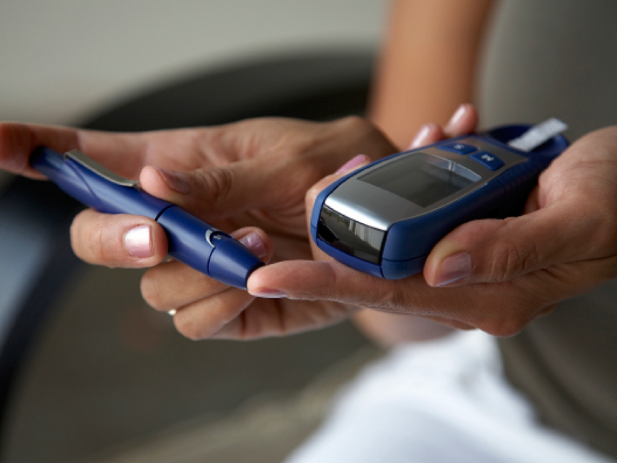 Woman taking blood sugar level w/glucometer