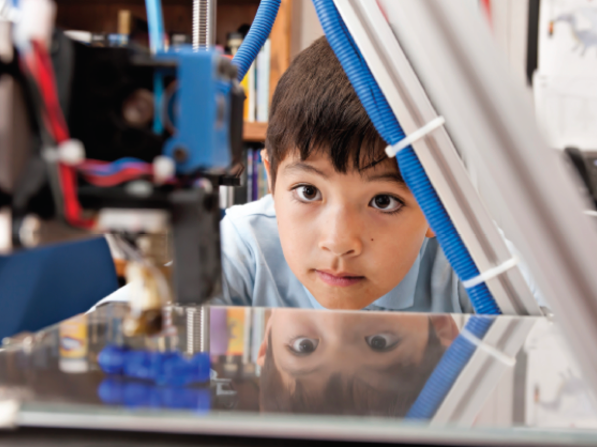 Young boy looking at a 3D printer