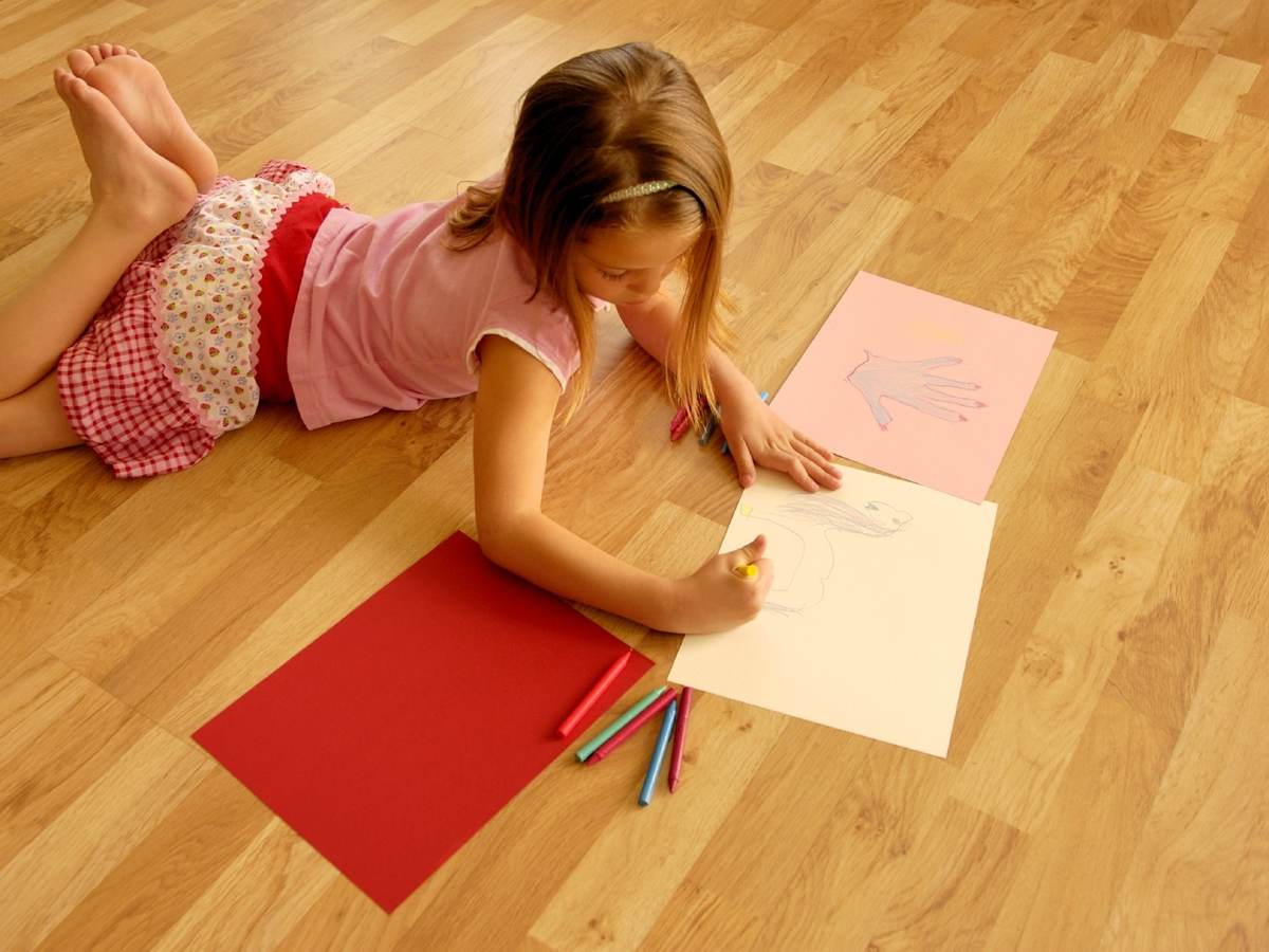 Girl coloring on a wood floor
