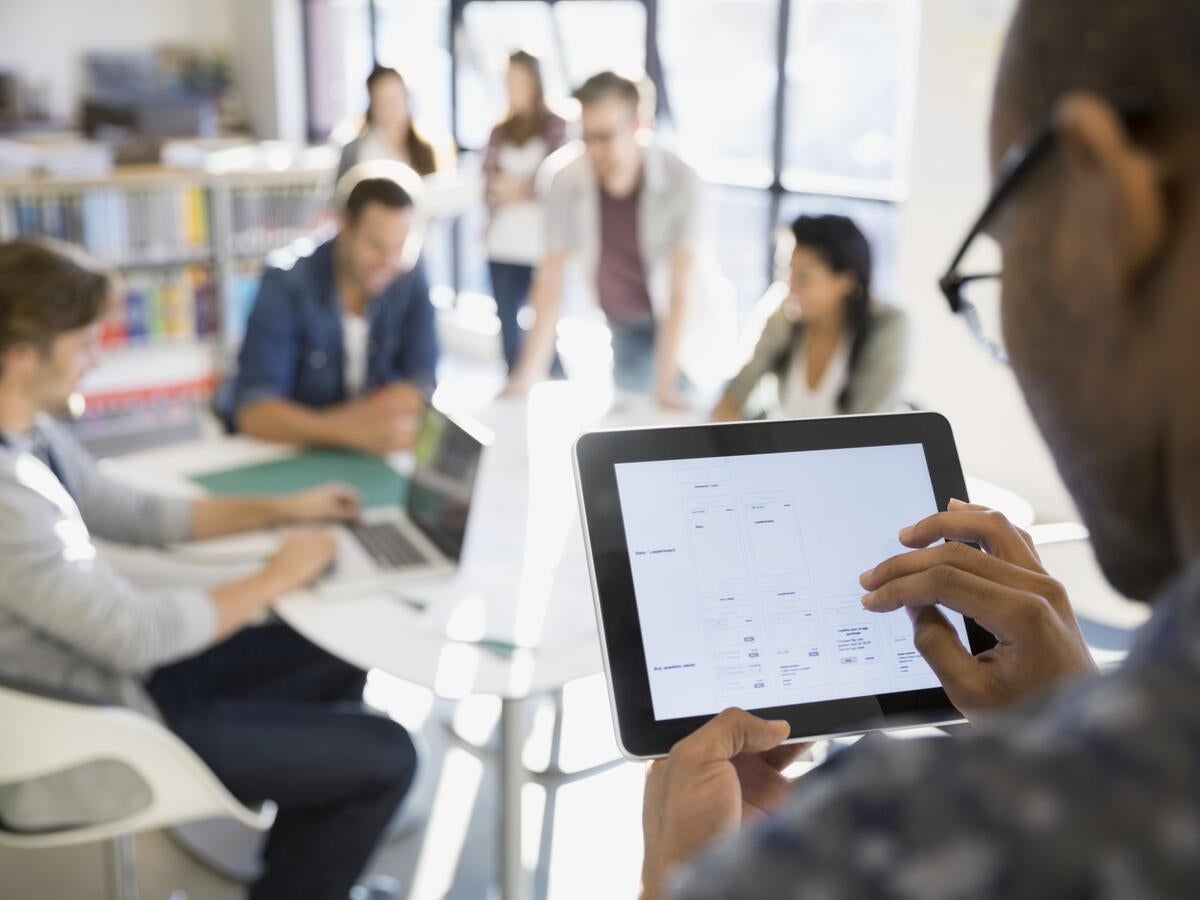 man using and tablet while presenting in front of a room