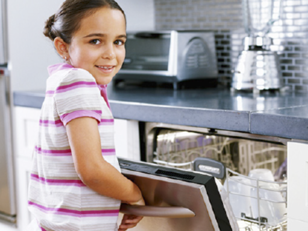 school age girl in a home kitchen opening dishwasher