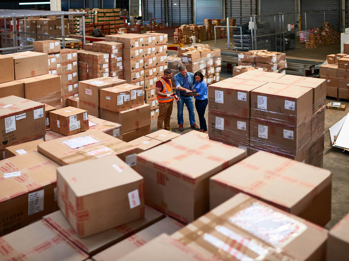 A few people in a warehouse surrounded in boxes.