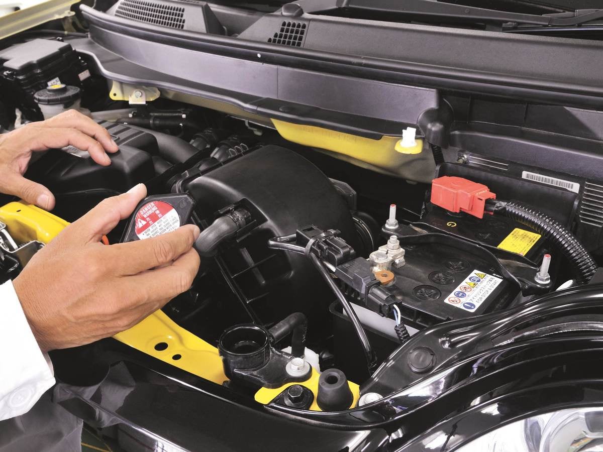 Inside hood of a car focusing on a part with a label