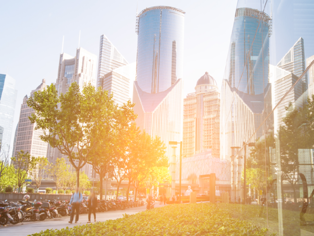 people walking through city park at sunset with tall buildings in the background
