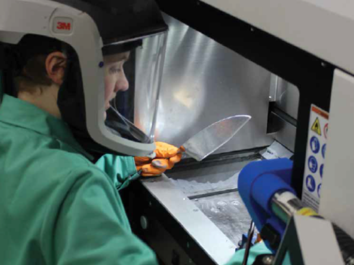 Person in green shirt with mask on in a lab