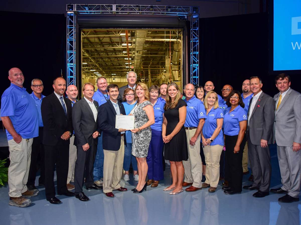 The BASF Zero Waste team stands in front of a mock-up of their facility as they accept their Zero Waste certification.