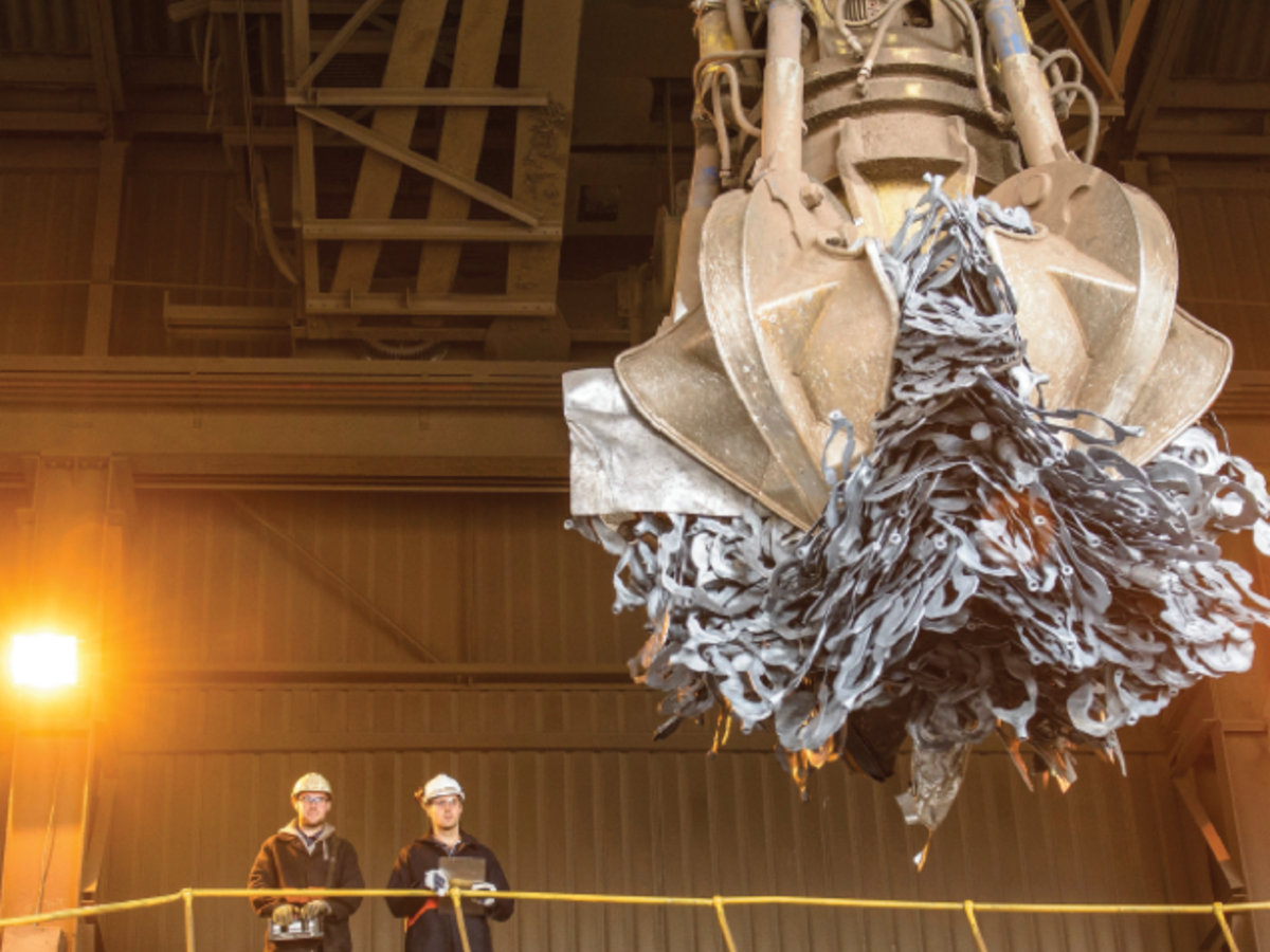 2 men overlooking a claw picking up recycleables