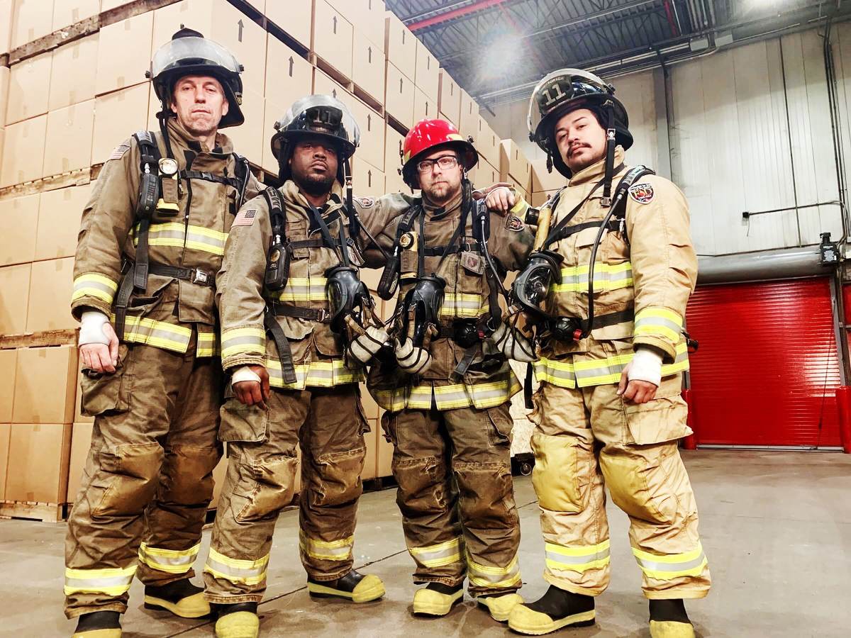 UL firefighters show off their gear in front of a mock warehouse. 