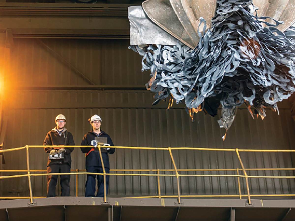 2 men overlooking a claw picking up recycleables