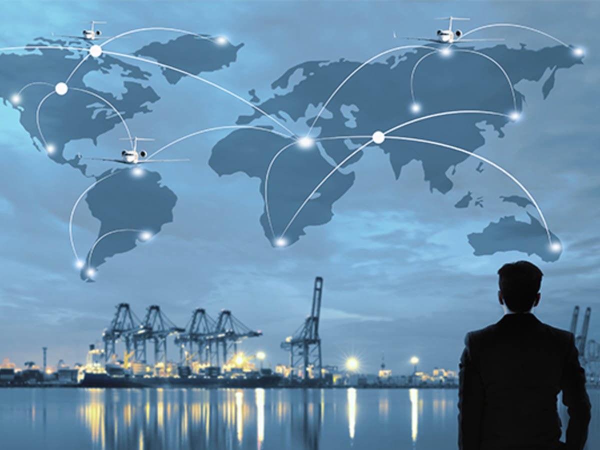 Outline map of an interconnected world displayed in the sky over water, being observed by a person standing on the shore.