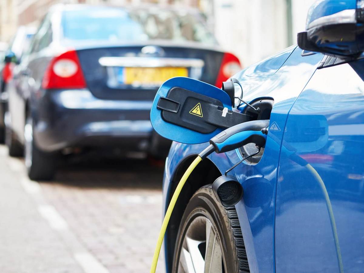 Blue electric vehicle is charging on a city street.
