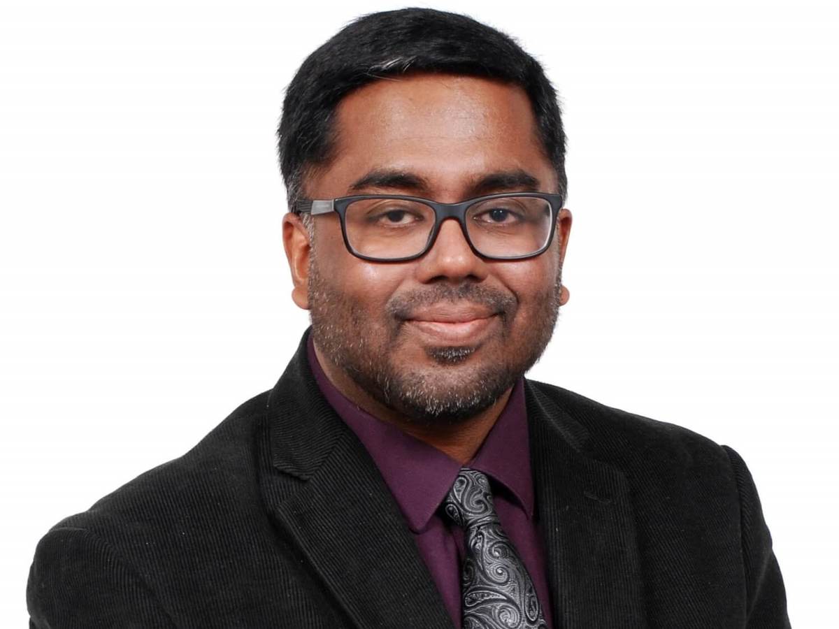 Anura Fernando wears a black jacket, burgundy shirt and grey tie for his corporate picture.