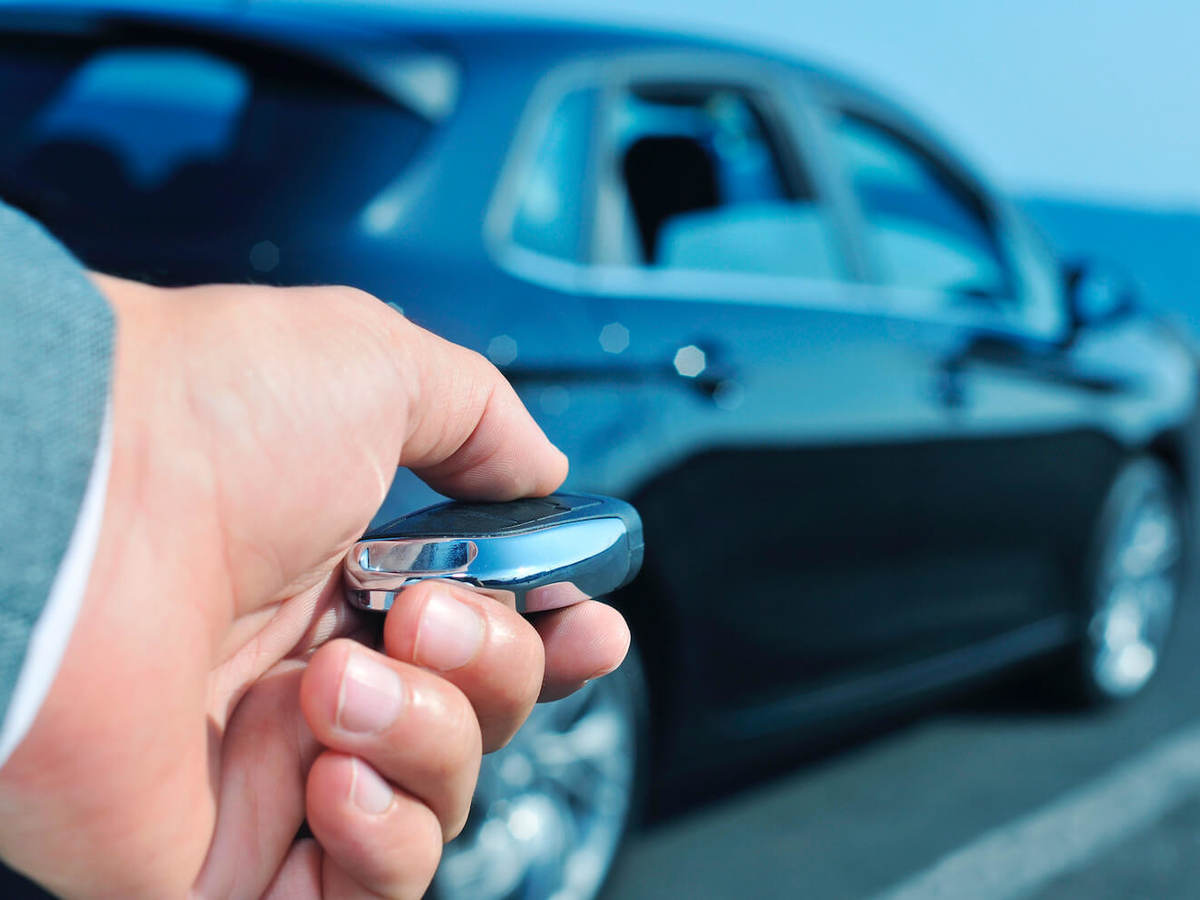 A man approaches a car with a key fob in his hand.