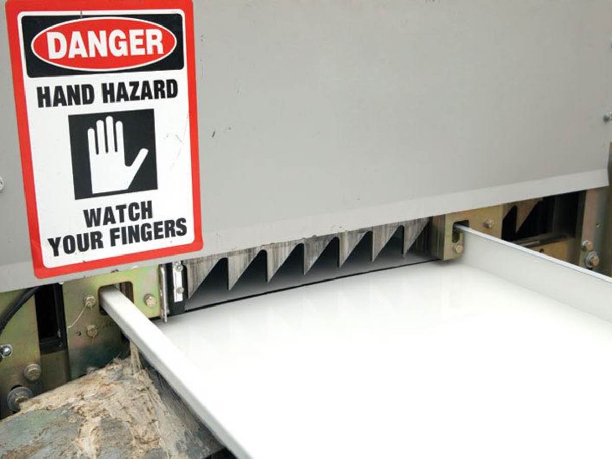 An industrial machine with a watch for fingers hazard sign warning facility workers.