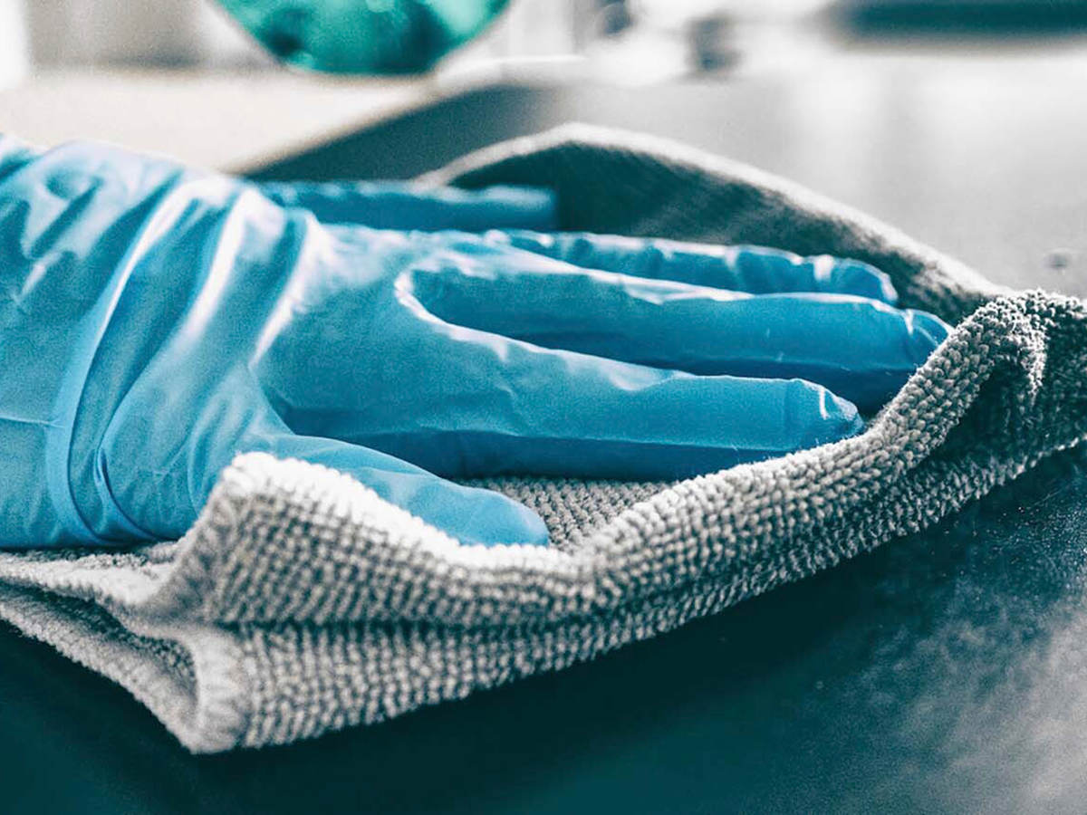 Photo of a person wearing gloves sanitizing a surface