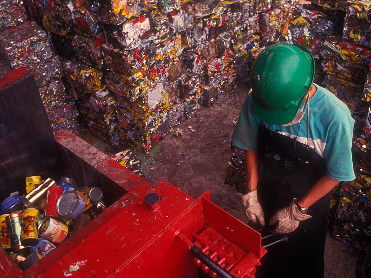 Man working trash compactor in landfill