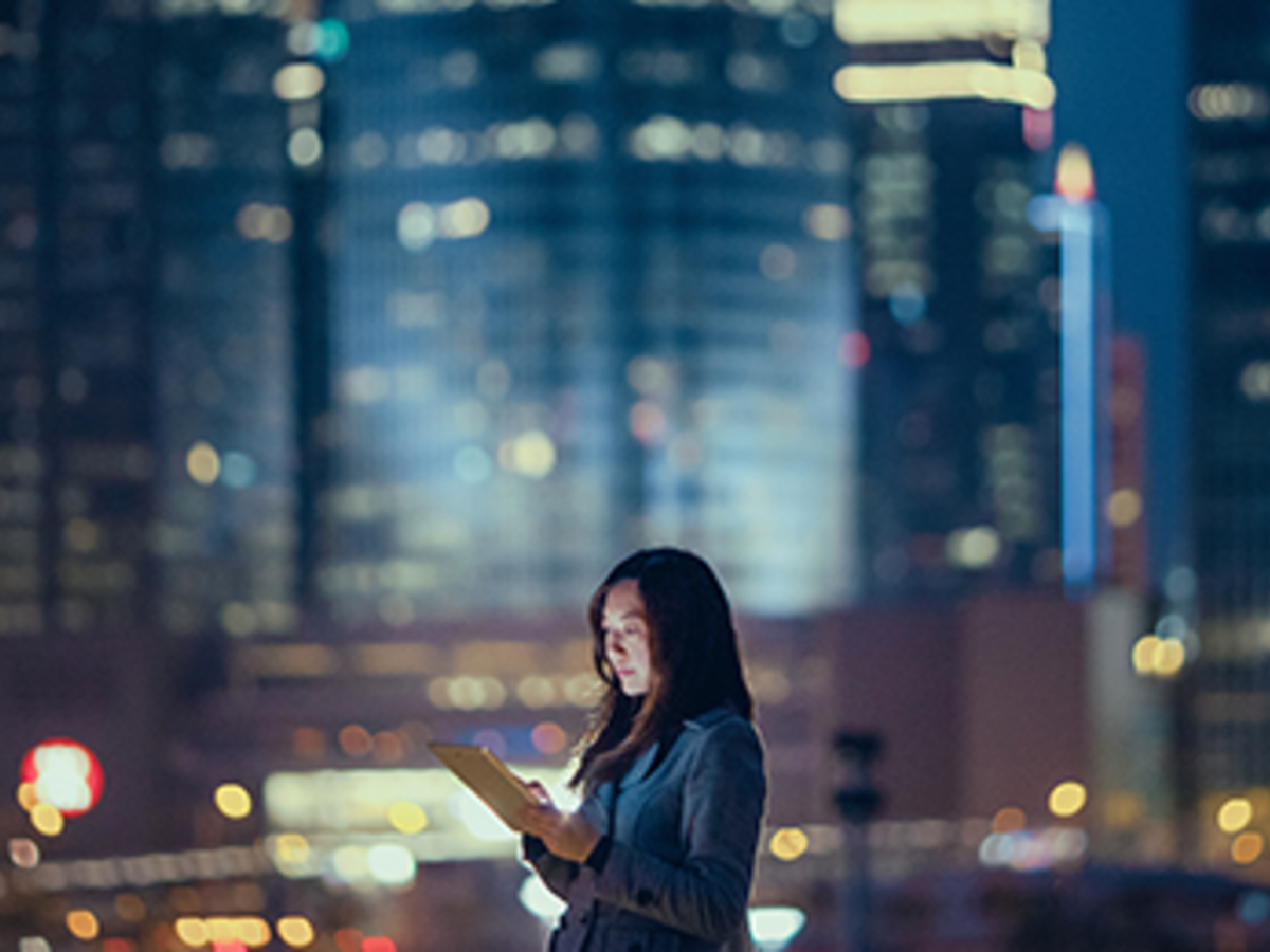 Woman looking at her tablet at night in the city
