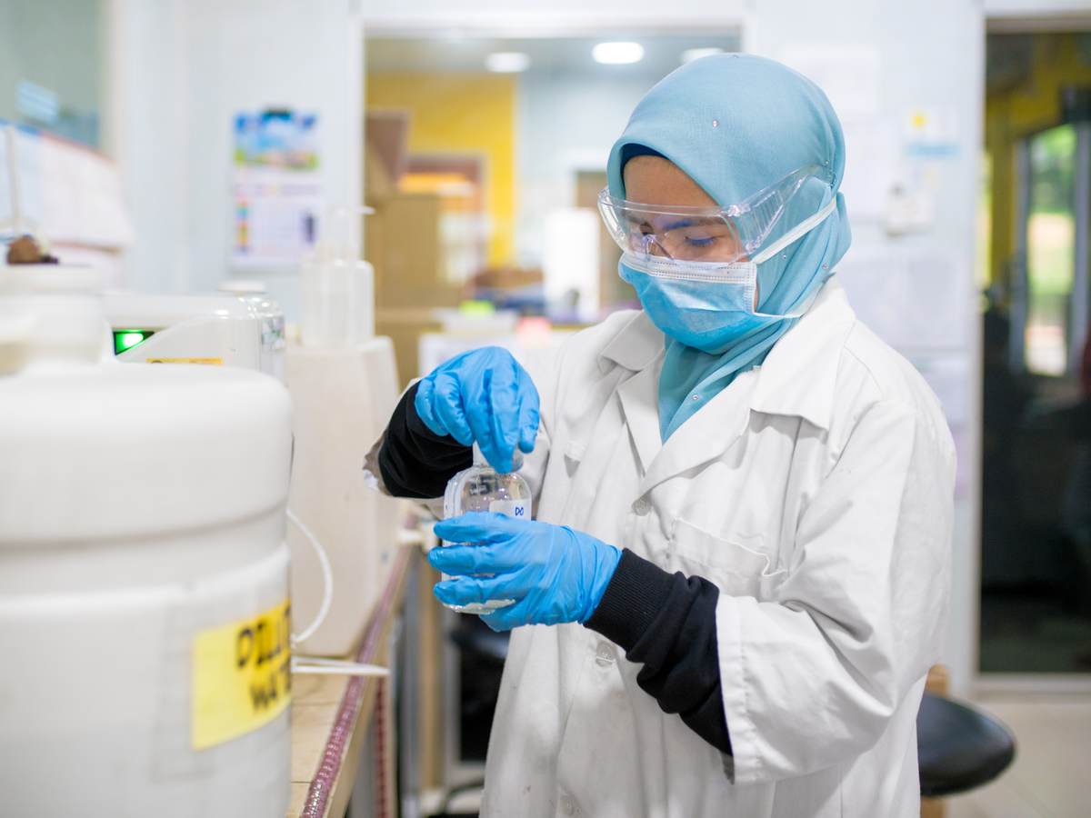 Female scientist in hijab and face mask works in a laboratory.