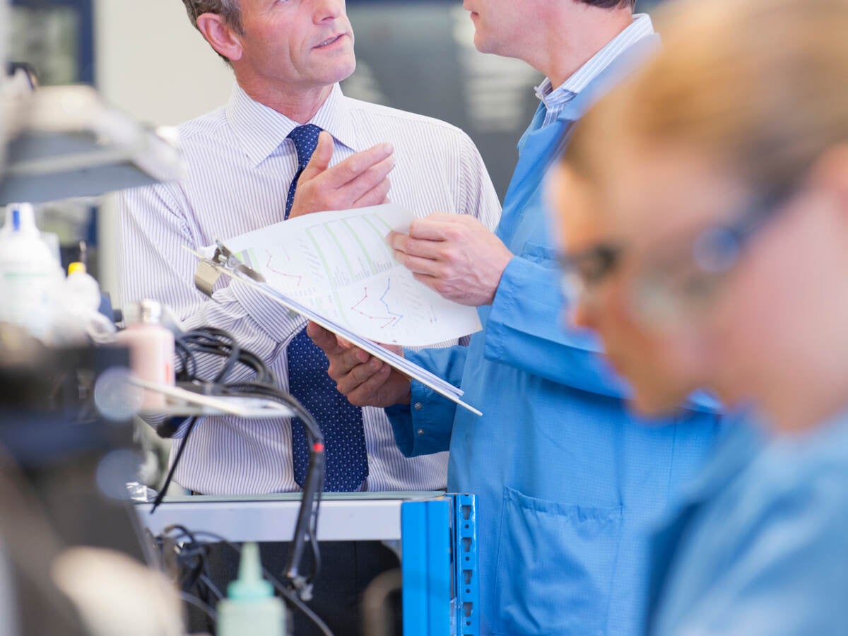 Businessman and engineer talking at production line in circuit board manufacturing plant.