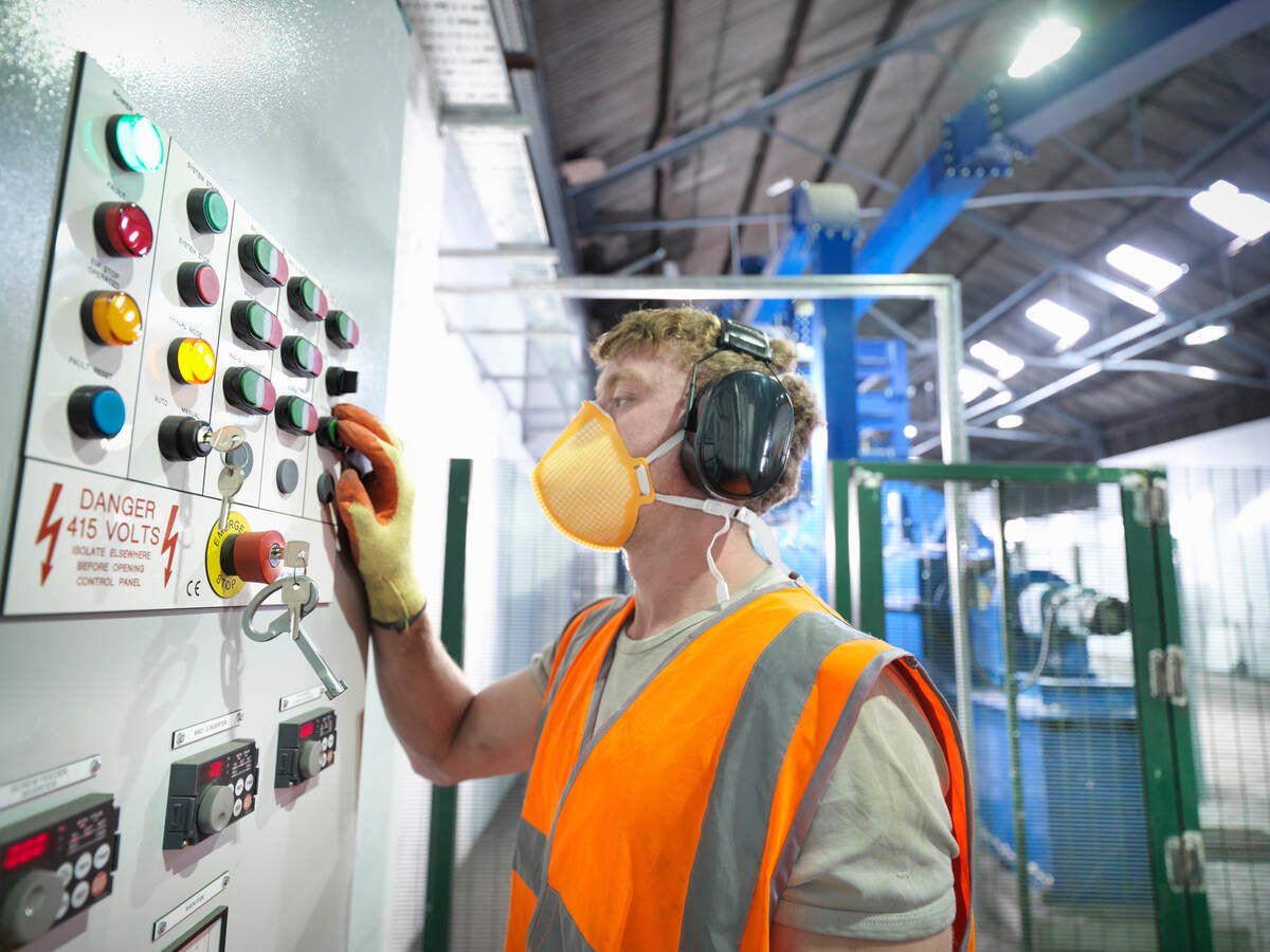 Worker at controls of metal ore grinding mill