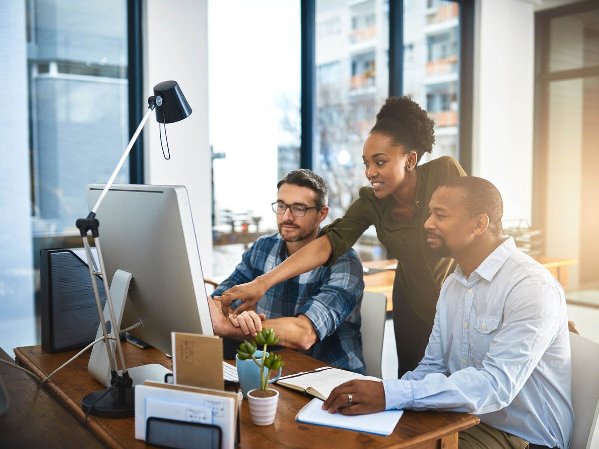 Three businesspeople working around a computer in the office