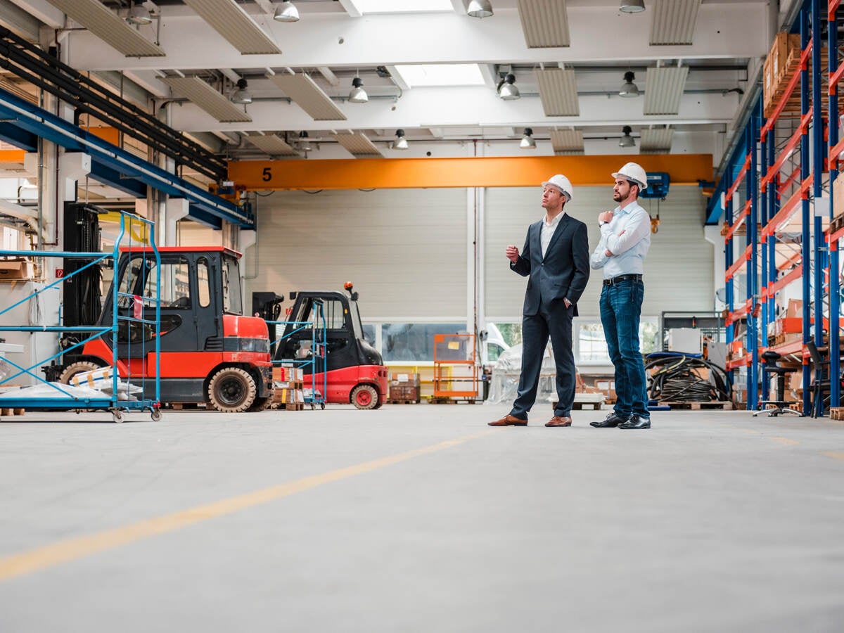 Two men wearing hard hats in factory shop floor