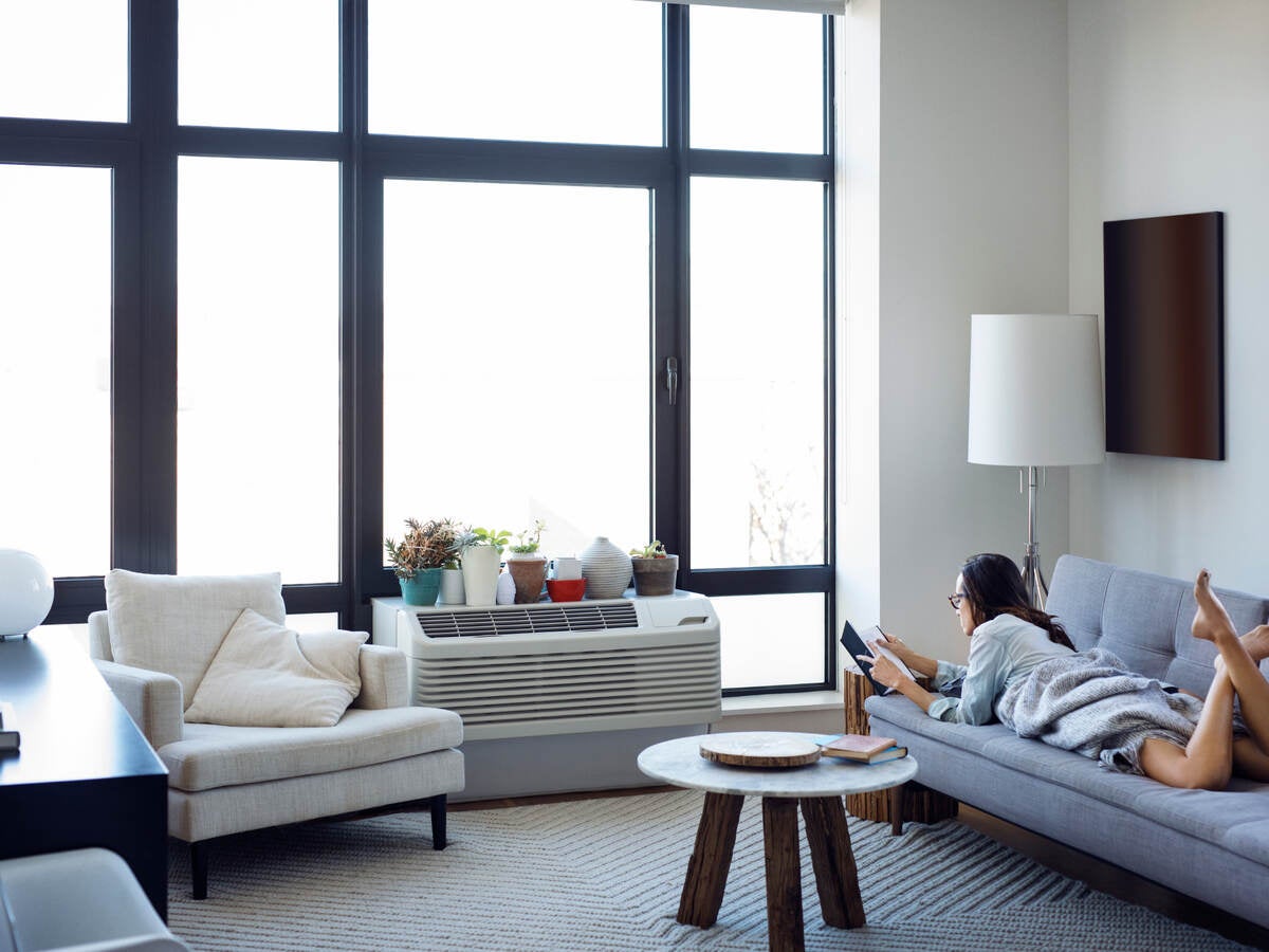 Woman reading book while lying on sofa at home