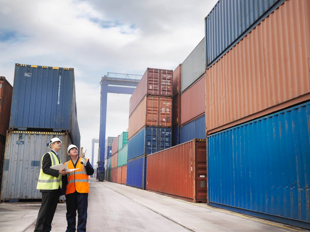 Two workers wearing a high visibility vest inspecting a shipping dock