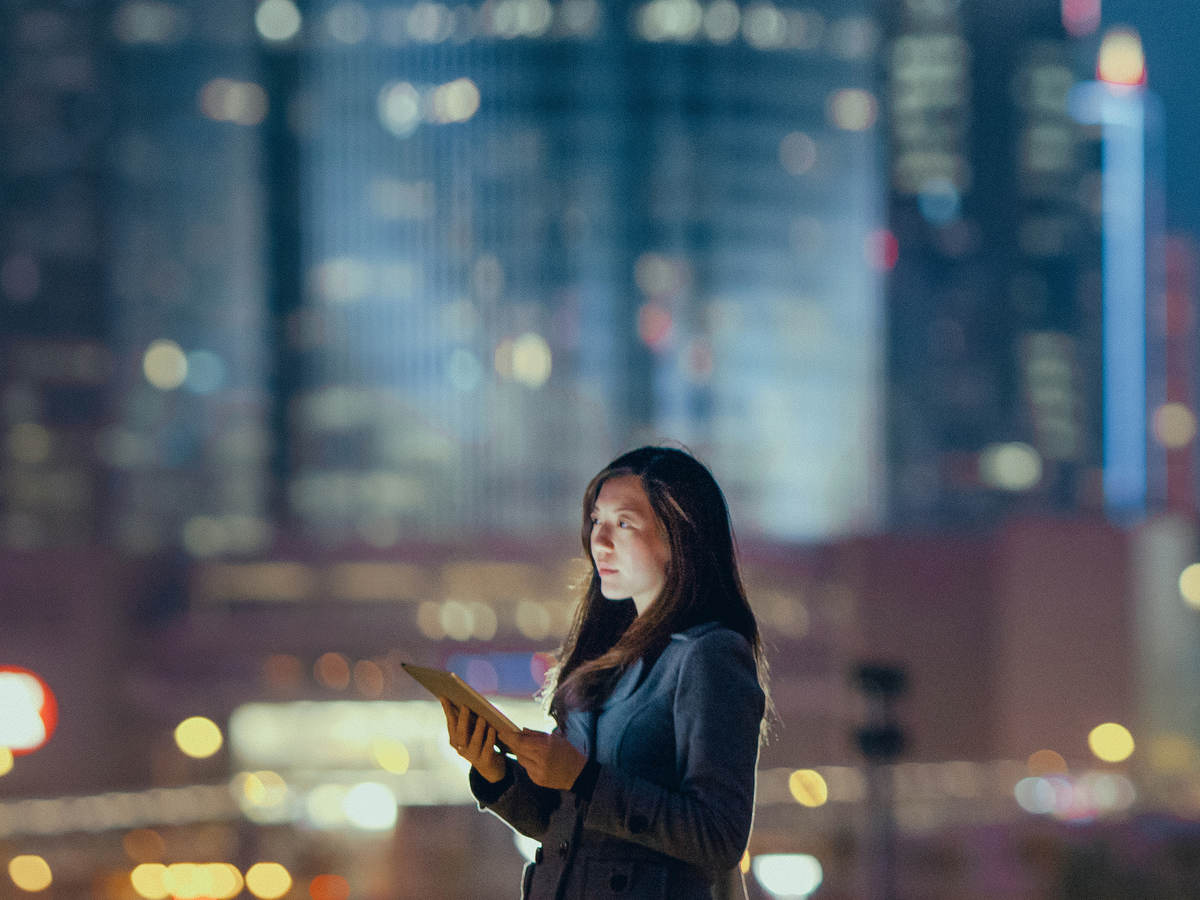Woman outside on rooftop alone with cityscape in the background.