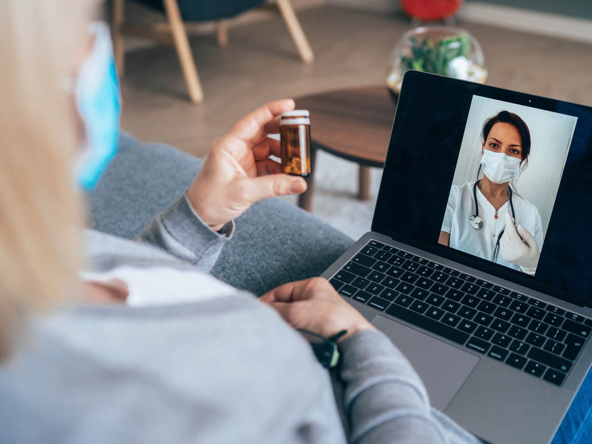 Senior woman isolated at home due to coronavirus epidemic having video call with family doctor, consulting about medicine