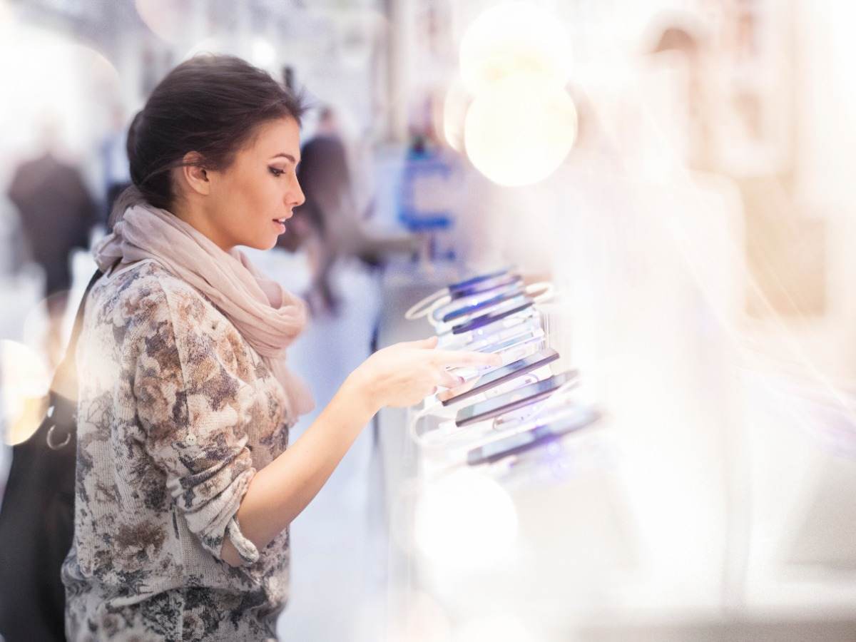 Consumer looking at several mobile devices in retail setting