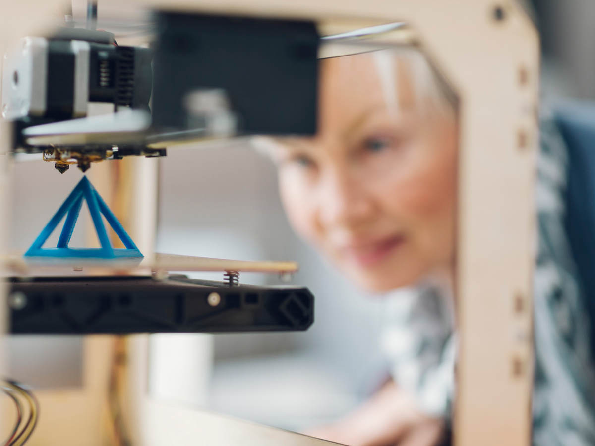 Photo of a woman working by a 3D printer
