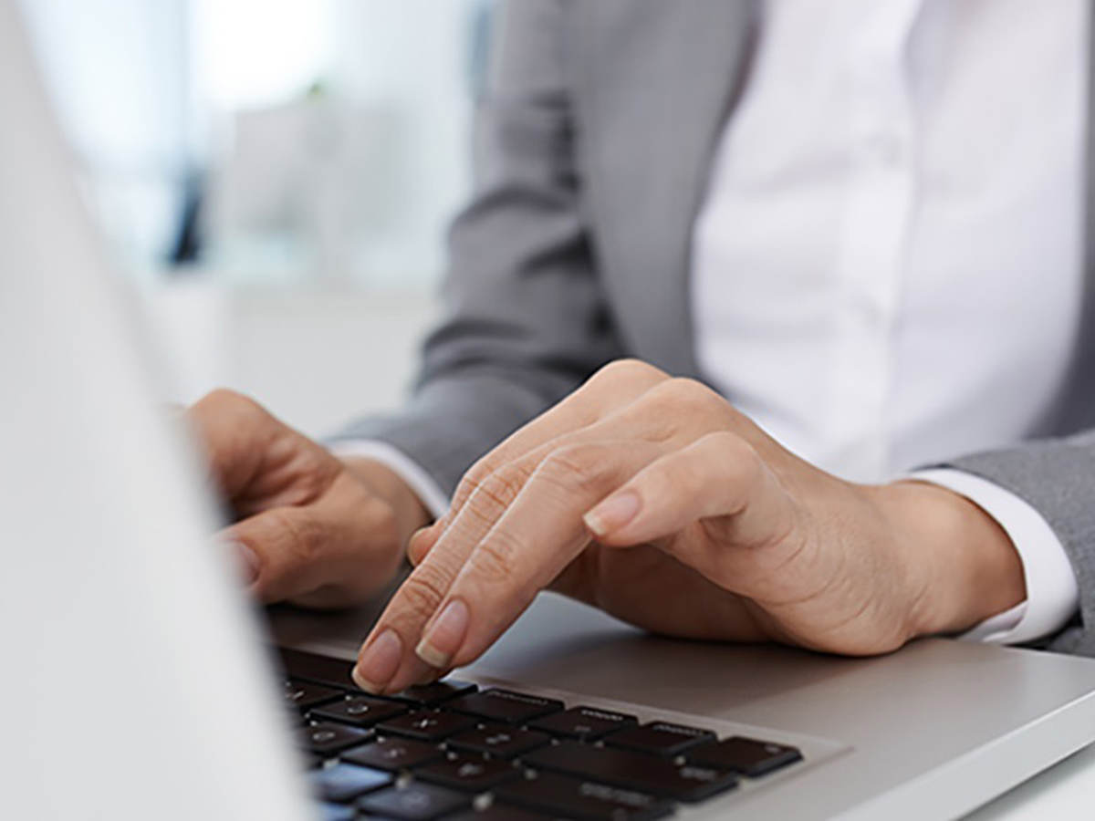 Photo of a woman typing on a laptop keyboard