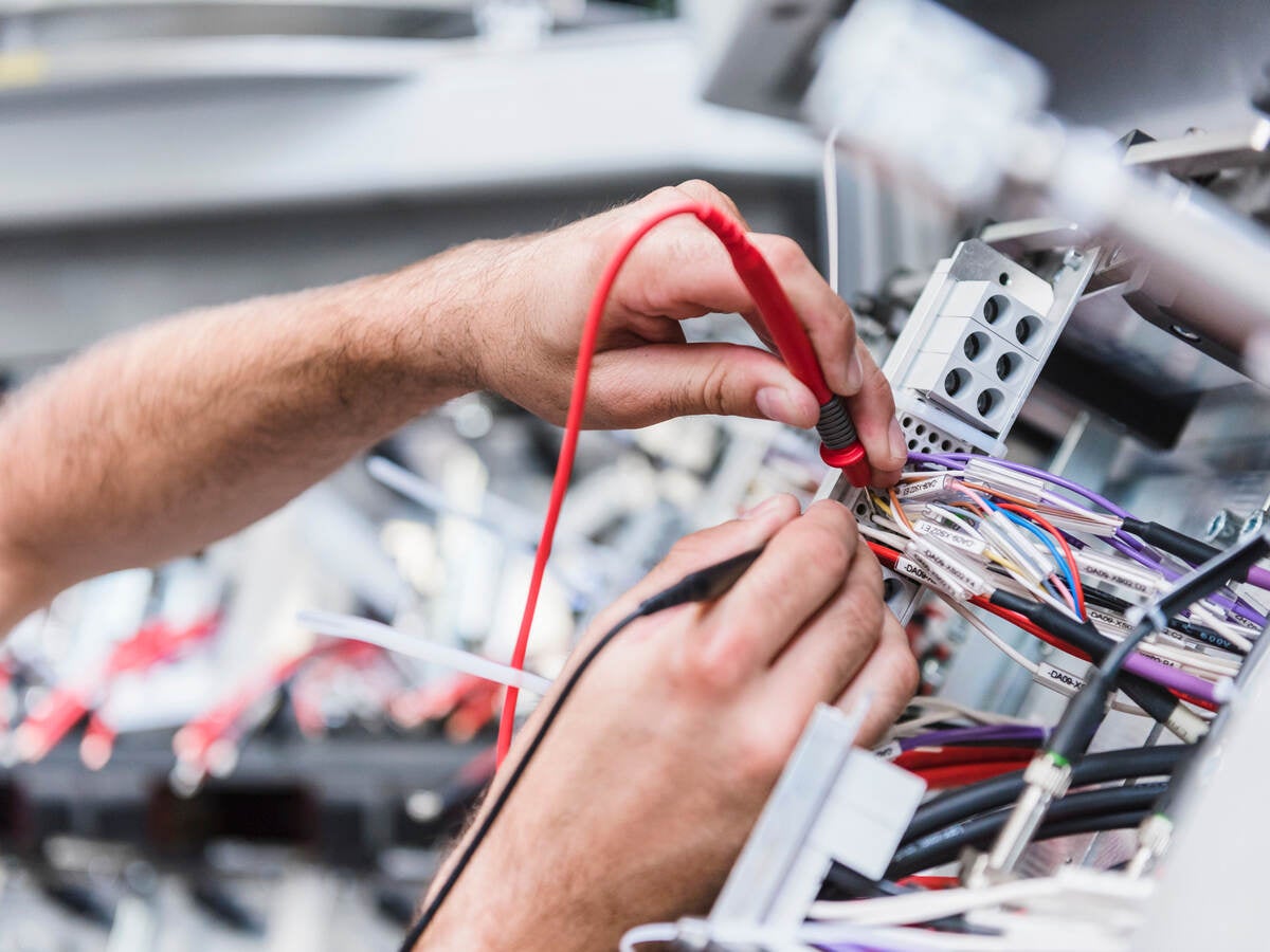Close-up of man using voltmeter in factory