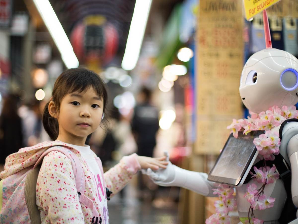 Asian girl touching robot's hand