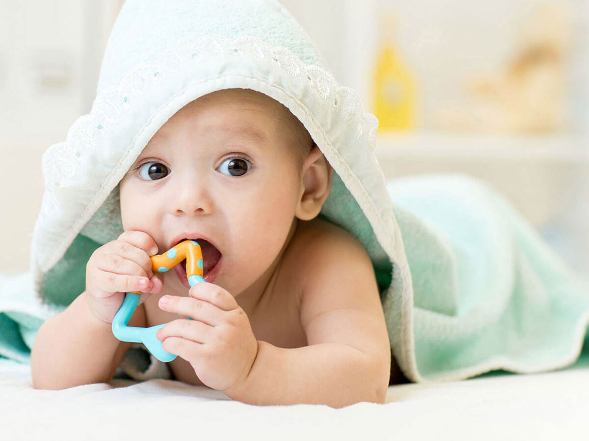 photo of a baby under a blanket playing with a toy