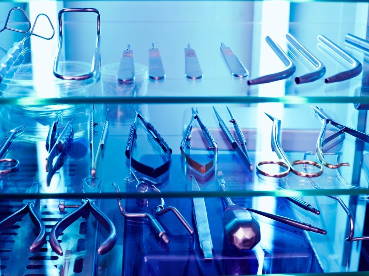 An array of medical devices sit within a cabinet basking in UV light.