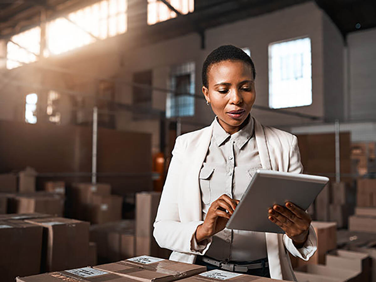 Business woman in a warehouse looking at a digital tablet